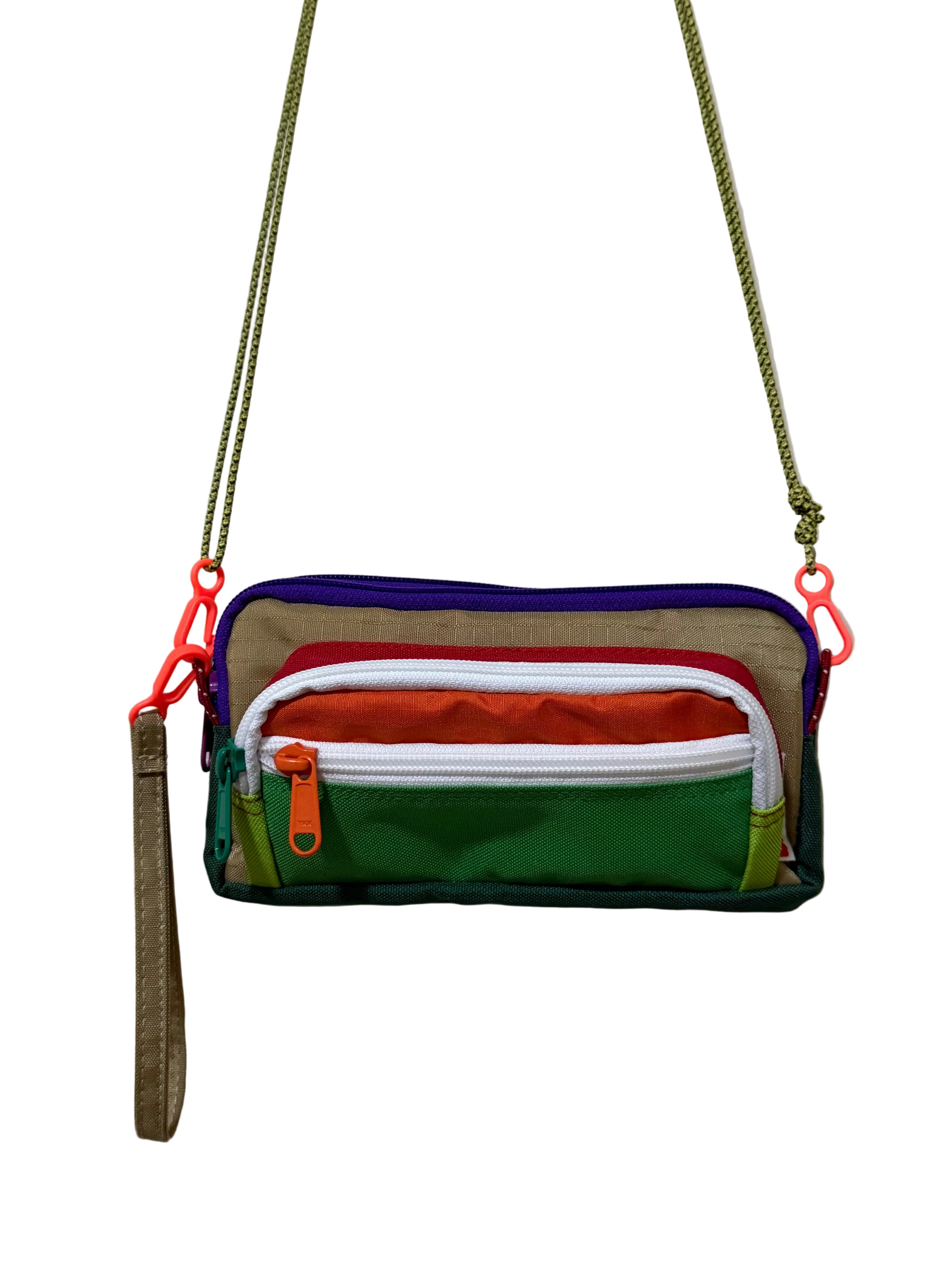 Colorful crossbody bag with multiple zippers on a plain background