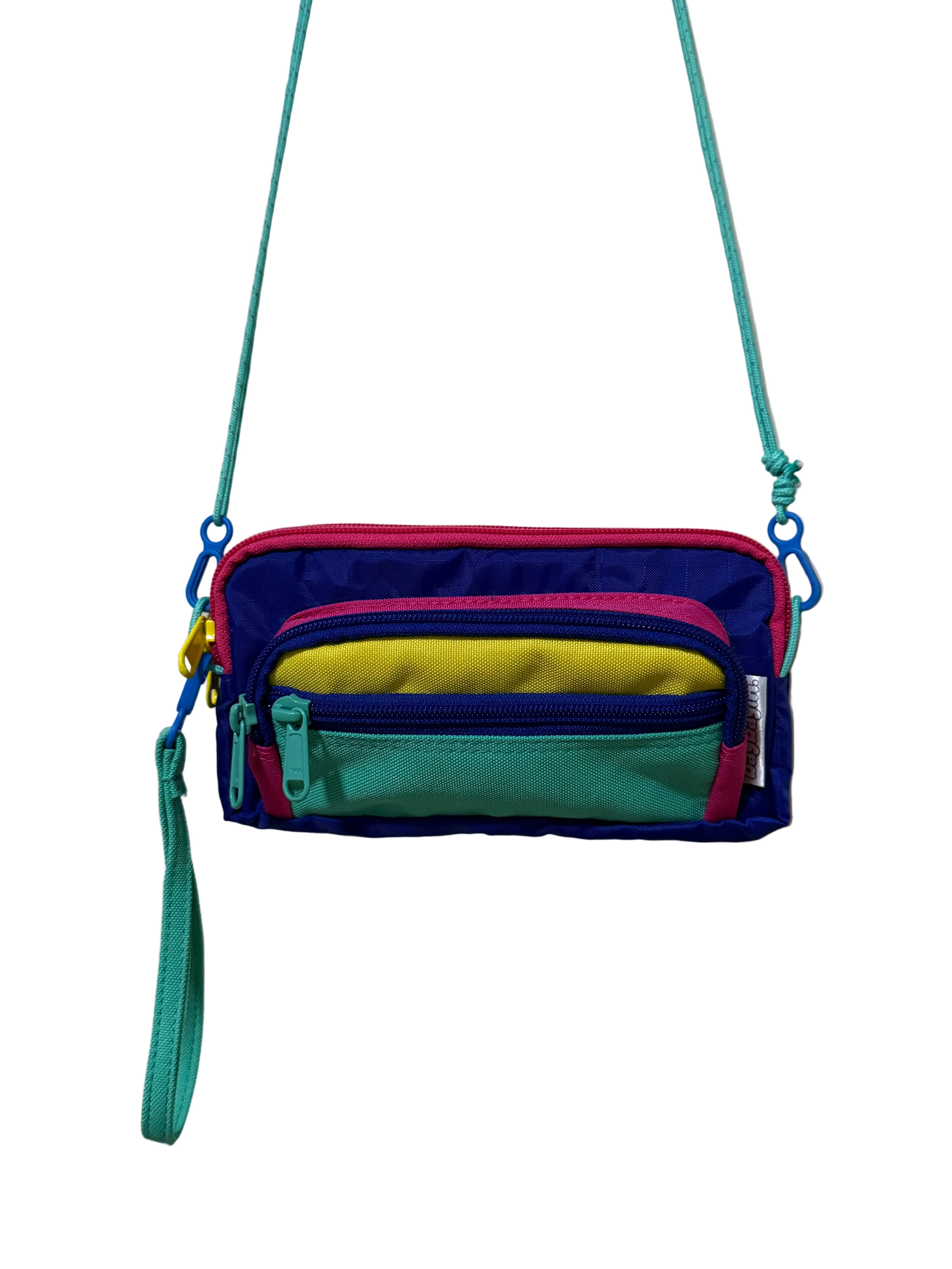 Colorful crossbody bag with multiple zippers on a light gray background