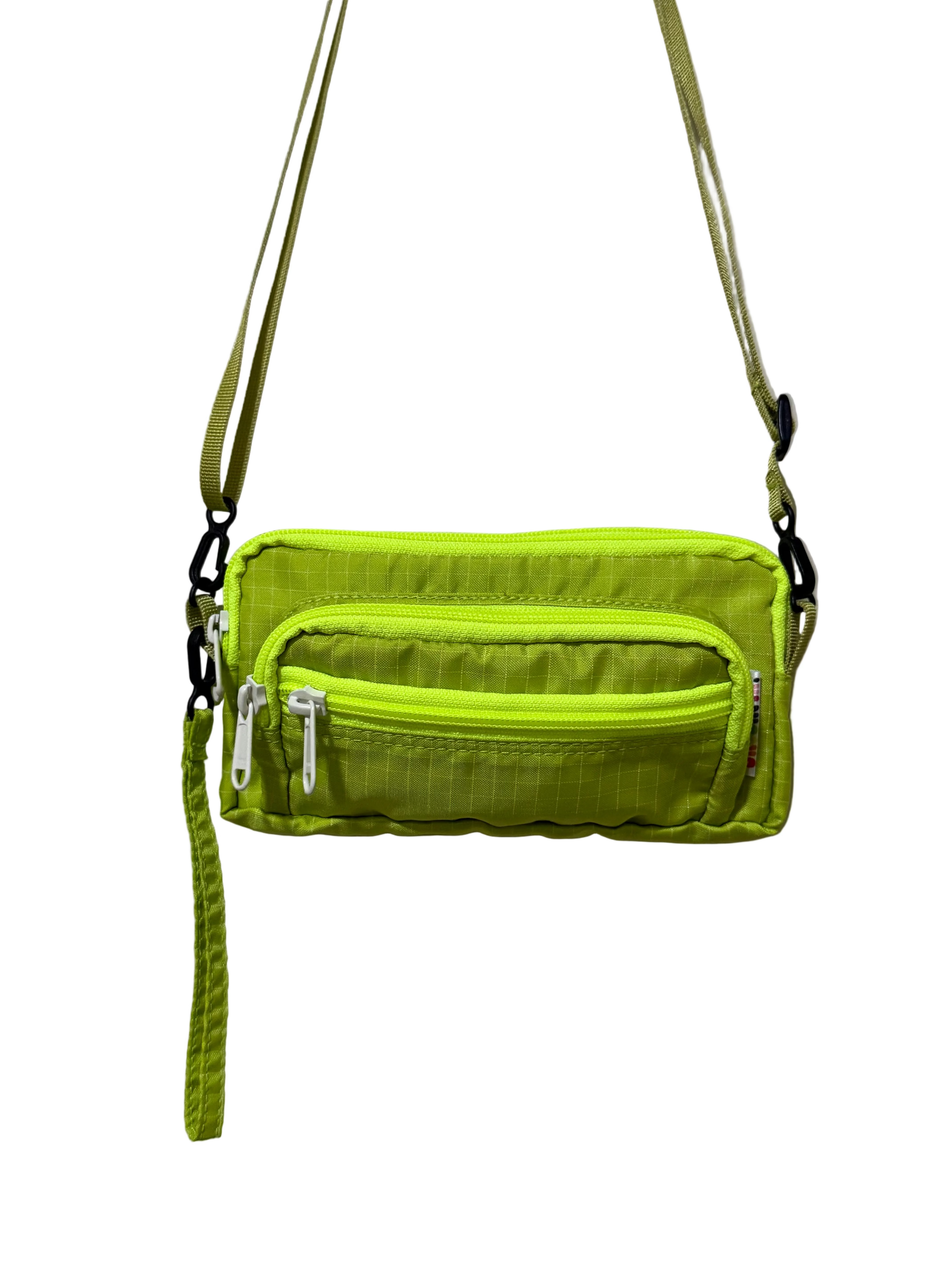 Green crossbody bag with multiple zippers on a light gray background